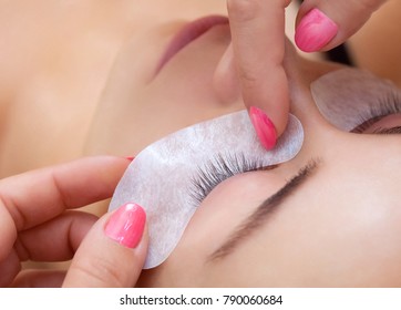 Eyelash extension procedure close up. Beautiful Woman with long lashes in a beauty salon.