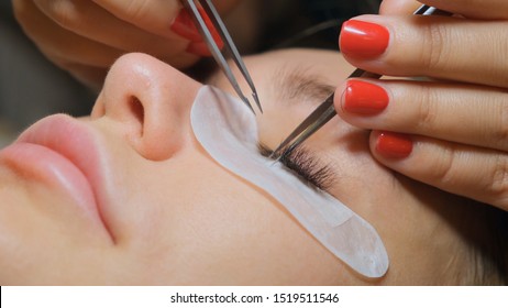 Eyelash extension procedure. The master grows long eyelashes. Female with extended eyelashes.