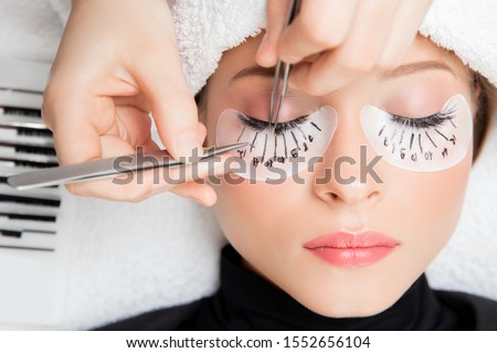Eyelash extension procedure. Master tweezers fake long lashes beautiful female eyes. Foto stock © 