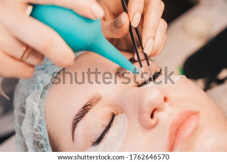 Eyelash extensions - the master dries glue with air - painstakingly delicate work