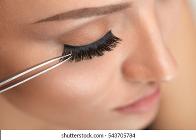 Eyelashes. Beautiful Woman Applying False Eyelashes With Tweezers. Closeup Of Young Female Model Face With Professional Facial Makeup, Smooth Skin And Long Black Thick Eye Lashes. High Resolution - Powered by Shutterstock