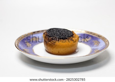 An eye-level side view of a round baked cake topped with a dark chocolate cookie served on a blue patterned saucer.