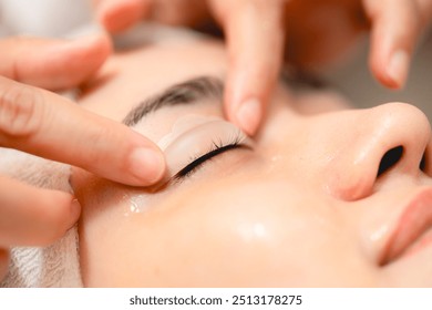 Eyelid Treatment. Anti-aging clinic woman closed eyes with gel treating upper eyelid procedure. Masseuse gentle massage client face and eyes - Powered by Shutterstock