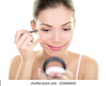 Eyeliner Eye Makeup Beauty Care Woman. Asian Girl Putting Eye Pencil Color On Eyes Looking In A Pocket Mirror Smiling Happy Isolated On White Background. Make Up With Multiracial Asian Caucasian Girl.