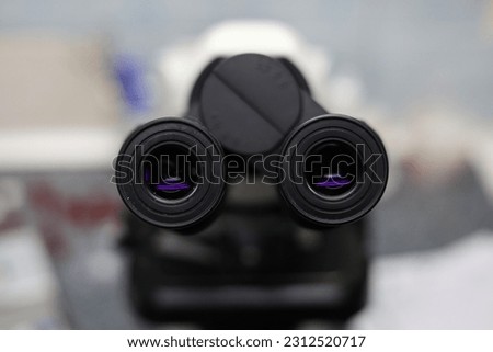 Eyepiece of a laboratory microscope in purple. Two black microscope eyepieces for examining biological material. There is a microscope in the laboratory to study the material.