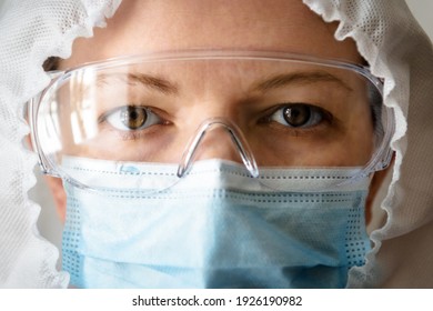 Eyes Of Doctor Wearing Goggles And Face Mask Due To COVID-19, Portrait Of Physician In Personal Protective Equipment (PPE) Close-up. Eyes Of White Young Woman, Nurses Look Closeup. Safety Concept.