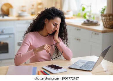 Eyes Fatigue. Sad Freelancer Woman Tired After Working Remotely On Laptop Computer At Home Office, Stressed Young Lady Sitting At Table In Kitchen Taking Off Glasses, Suffering Headache, Free Space