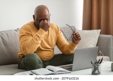 Eyes Fatigue. Tired Senior Black Man Rubbing Nosebridge Having Eyesight Problems And Headache Working On Laptop Computer Sitting On Sofa Indoors. Glaucoma, Health Issues In Older Age