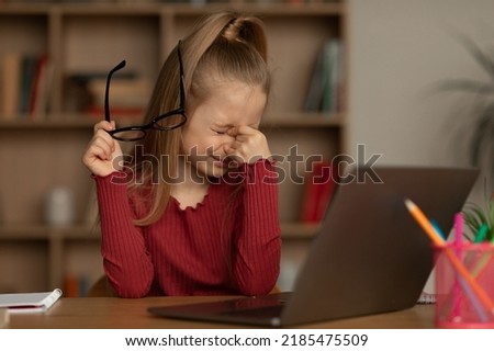 Eyes Health Problem. Little Girl Taking Off Eyeglasses Massaging Nosebridge Having Poor Eyesight Sitting At Laptop Computer Learning Online At Home. Poor Sight Concept. Selective Focus