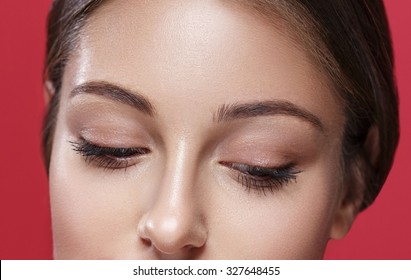 Eyes Looking Down Young Beautiful Woman Face Portrait With Healthy Skin On Red Background