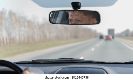 The eyes of a mature driver in the rearview mirror looking at the road while driving - Shutterstock ID 1015443739