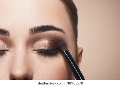 Eyeshadow aplicar, maquillaje para los ojos cerrar. La cara de modelo femenina con maquillaje de moda, concepto de belleza