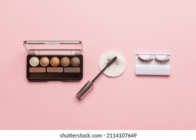 Eyeshadows, Mascara, False Eyelashes And Used Cotton Pad On Pink Background