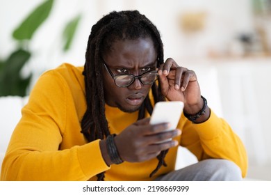 Eyesight Problems Concept. Young Black Man Wearing Eyeglasses Reading Message On Smartphone, African American Guy Looking At Cellphone Screen, Taking Off Glasses And Squinting Eyes, Closeup