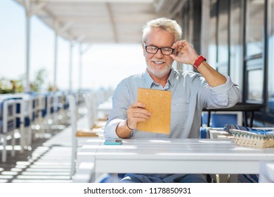 Eyesight Problems. Happy Cheerful Man Fixing His Glasses While Trying To Read The Menu