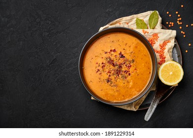 Ezogelin Soup in black bowl on dark slate table top. Turkish cuisine traditional Çorba dish with red lentils, bulgur and rice. Copy space