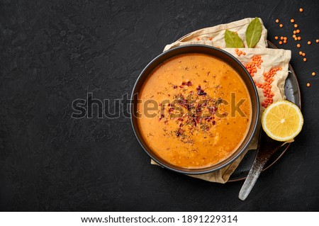Ezogelin Soup in black bowl on dark slate table top. Turkish cuisine traditional Çorba dish with red lentils, bulgur and rice. Copy space