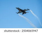 F-16 High-Speed Pass. A Solo Turk F-16 fighter jet in mid-air, performing a high-speed pass with smoke trails trailing behind it. The jet is angled upwards, creating a sense of dynamism and speed