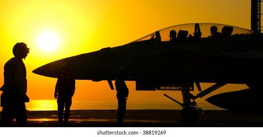 An F-18 Super Hornet readies to launch from an aircraft carrier at sunset