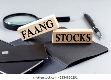 FAANG STOCKS text on a wooden block on black notebook , business concept