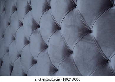 Fabric background with capitone. Capitone in gray fabric. Capitone from sofa or bed close-up view. Gray fabric pattern. Abstract background for furniture. Background of photo of upholstered furniture