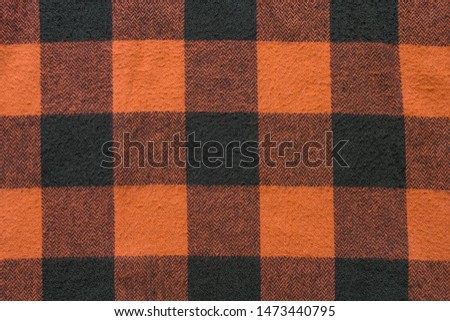 Fabric with black and orange cages pattern. Plaid material. Clothes background