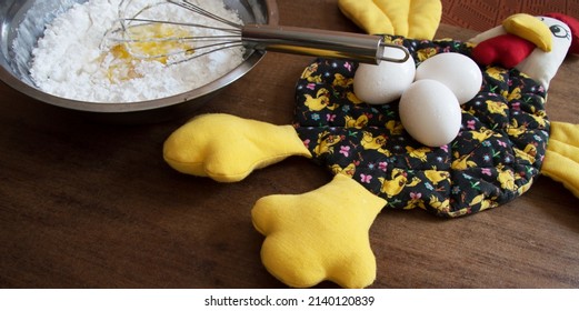 Fabric Chicken With Three Eggs On Top And Bowl With Sprinkle And Yolks Mixed In The Center By A Whisk That Is Dirty With This Mixture, All On Top Of A Brown Wooden Table