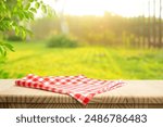 Fabric cloth placemat or checked red  on wood table counter top and outdoor lawn background. for food and drink  product display advertising design