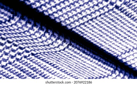 The fabric is dense, warm with a checkered pattern in blue. Checkered yarn in dark blue. Background texture pattern.