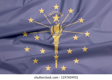 Fabric Flag Of Indiana. Crease Of Indiana Flag Background, The States Of America, A Gold Torch Surrounded By An Outer Circle Of Stars, An Inner Semi Circle Of Stars, The Word 'Indiana'.