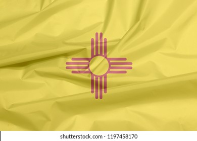 Fabric flag of New Mexico. Crease of New Mexico flag background, The states of America, The red and yellow of old Spain. The ancient Zia Sun symbol in red.
