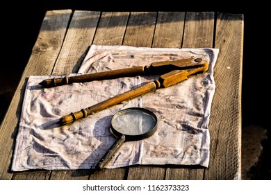 Fabric Map and magnifying glass and drafting compass on distressed wooden table
