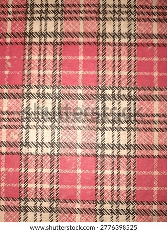 A fabric or printed surface displaying a bold plaid pattern composed of intersecting lines in red, black, and off-white, forming distinct square and rectangular blocks.
