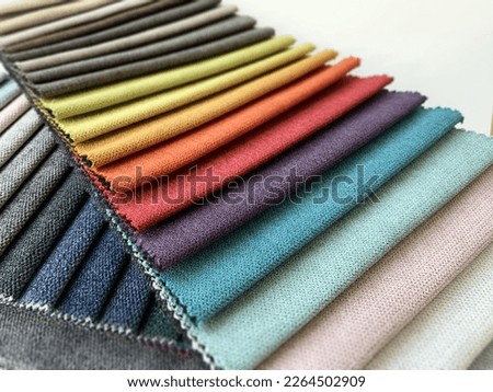 Fabric samples in different colors are laid out for choosing from. A variety of shades of upholstery material for furniture, curtains and interior. Fabric texture close-up. A set of colorful textile