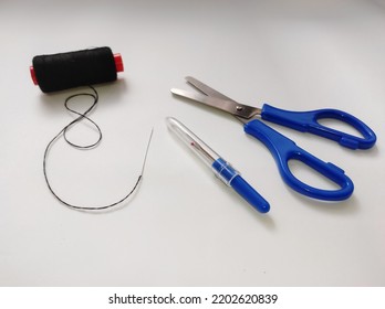 Fabric Scissors, Seam Ripper, Black Thread, Hand Sewing Needle Isolated On A White Background.