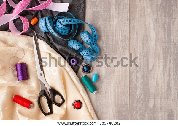 Fabric and sewing items. Tailors scissors, tape\
measure, spools of thread, buttons, ribbons, line needed for sewing\
clothes and tailoring. Create and design fashion. Needlework and\
sewing clothes.