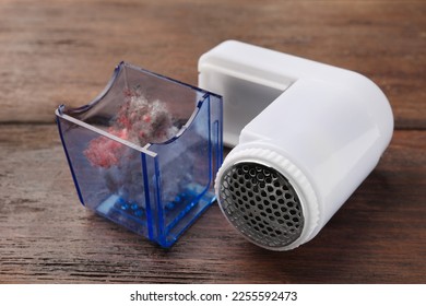 Fabric shaver with fuzz on wooden table, closeup. Modern appliance - Shutterstock ID 2255592473