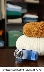 Fabric shaver and knitted clothes on wooden table indoors - Shutterstock ID 2257367779
