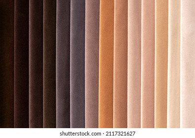 Fabric Swatches In Different Colors Are Stacked For Selection. A Variety Of Shades Of Upholstery Material For Furniture And Interior. Fabric Texture Close Up. A Set Of Multi-colored Rolls Of Material.