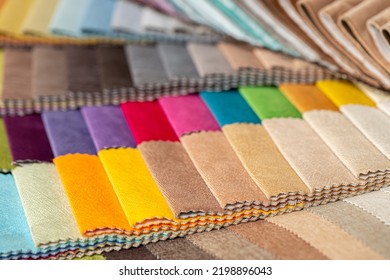 Fabric Swatches In Different Colors Are Stacked For Selection. A Variety Of Shades Of Upholstery Material For Furniture And Interior. Fabric Texture Close Up. A Set Of Multi-colored Rolls Of Material.