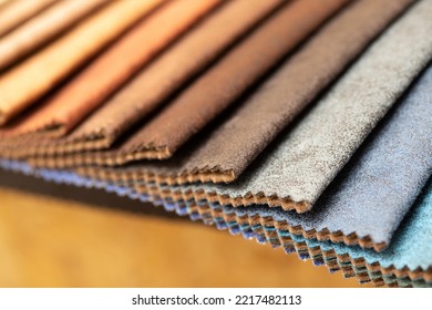 Fabric Swatches In Different Colors Are Stacked For Selection. A Variety Of Shades Of Upholstery Material For Furniture And Interior. Fabric Texture Close Up. A Set Of Multi-colored Rolls Of Material.