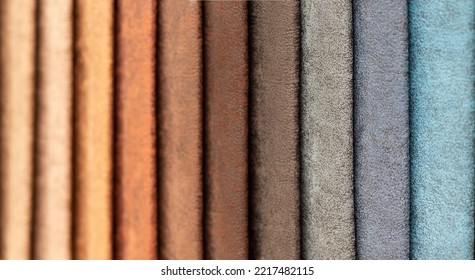 Fabric Swatches In Different Colors Are Stacked For Selection. A Variety Of Shades Of Upholstery Material For Furniture And Interior. Fabric Texture Close Up. A Set Of Multi-colored Rolls Of Material.