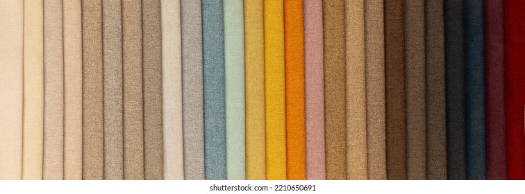 Fabric Texture Close Up. Fabric Swatches In Different Colors Are Stacked For Selection. A Variety Of Shades Of Upholstery Material For Furniture And Interior. A Set Of Multi-colored Rolls Of Material.