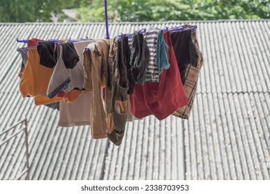 Fabrics and clothes that are drying on the roofs of houses. Clothesline hanger on house settlement rooftop. Clothes drying process in the sun. - Powered by Shutterstock