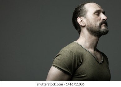 Fabulous at any age. Profile portrait of charismatic muscular 40-year-old man standing over dark gray background. Hair brushed back. Rocker, biker style. Close up. Copy-space. Studio shot - Powered by Shutterstock