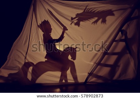 Fabulous the shadow of the little Prince on horse with sword and dragon. Theatre. Childhood. Tale.