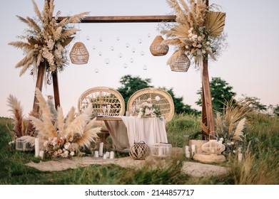 Fabulous wedding for two. Wedding table set up in boho style with pampas grass and greenery, and two straw chair in field with sunset view - Shutterstock ID 2144857717