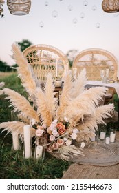 Fabulous wedding for two. Wedding table set up in boho style with pampas grass and greenery, and two straw chair in field with sunset view
