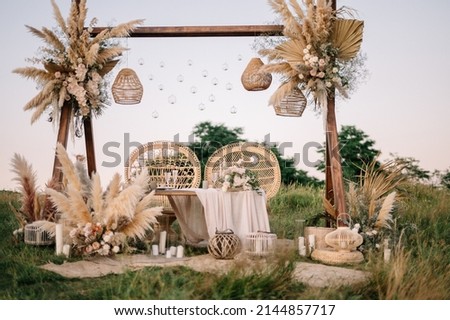 Fabulous wedding for two. Wedding table set up in boho style with pampas grass and greenery, and two straw chair in field with sunset view