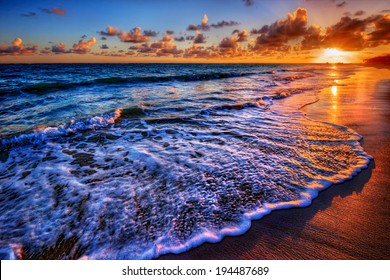 Fabulously shaped wave breaking on a sandy beach at sunrise